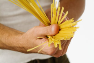 Close-up of uncooked spaghetti in a man's hands